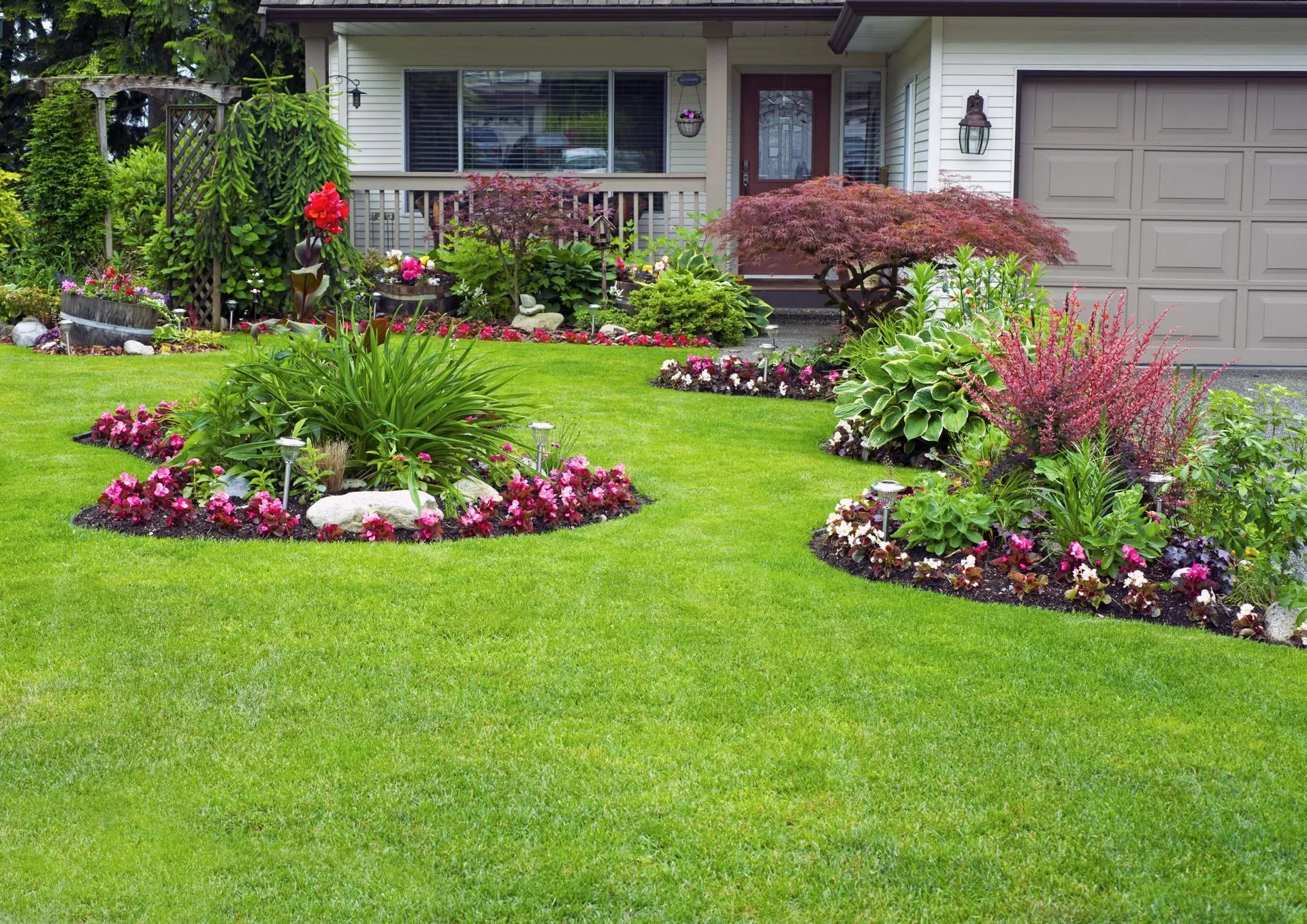 Front yard with a green lawn and flower beds